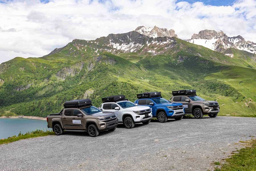 Vier Geländewagen mit VICKYWOOD Dachzelten stehen vor einem Alpenpanorama.
